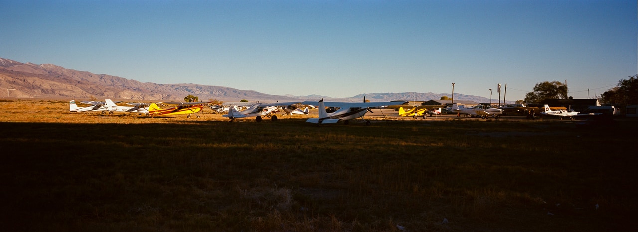 Small aircraft parked in a line beneath desert mountains
