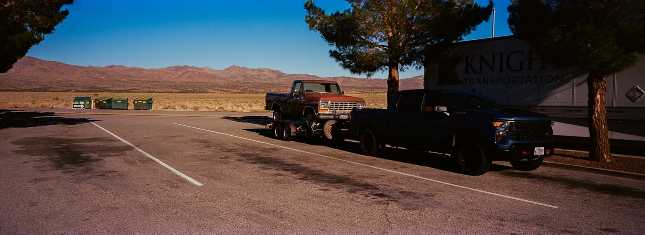 Parked trucks beside an open road and distant desert hills