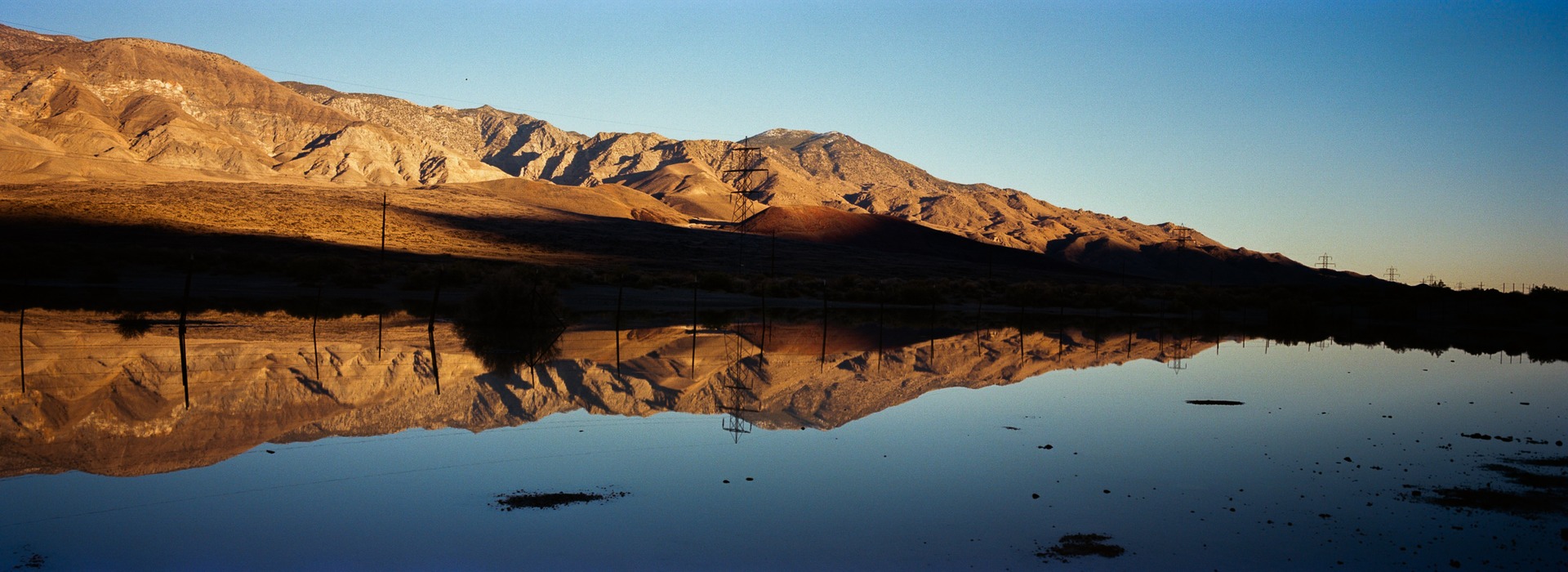 A sunlit desert ridge reflected in still water