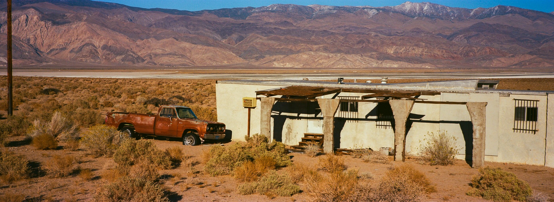 A roadside building and pickup below the broad desert valley